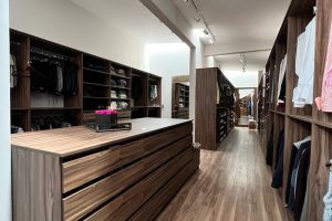 Vestidor con isla en acabado corso con cajones, área de colgado, repisas y puertas diseñado por California Closets