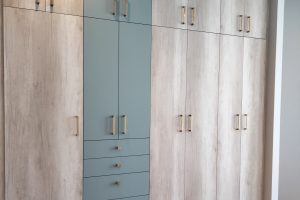 Closet de pared con cajones y compartimentos con puertas, agarraderas en color dorado diseñado por California Closets