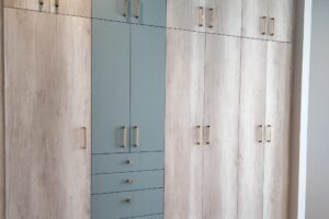 Closet de pared con cajones y compartimentos con puertas, agarraderas en color dorado diseñado por California Closets