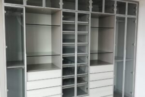 Clóset de pared en color blanco con cajones y espacios con puertas de vidrio diseñado por California Closets
